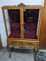 A mid 20th century walnut display cabinet having two doors above drawers, internal glass and