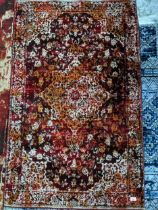 A contemporary small floral patterned machine woven rug on a red ground 147cm x 92cm Location: