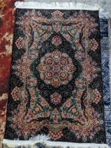 A contemporary small Persian style rug, machine woven on a black ground, floral pattern with a