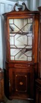 A George III mahogany and boxwood inlaid corner cabinet having a broken swan neck pediment above