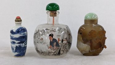 Three Chinese snuff bottles to include a brown agate relief carved bottle decorated with a cat and
