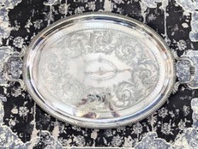 A large twin handled oval silver plated serving tray, engraved with floral decoration and a