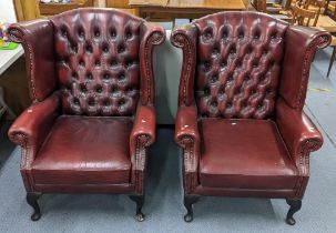 A pair of reproduction button back red leather upholstered Chesterfield wingback armchairs Location: