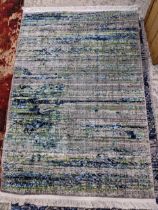 A contemporary small abstract pattern rug in greens and blues on a grey ground 158cm x 101cm