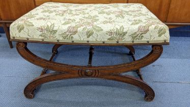 An early 20th century mahogany cross framed stool having scrolled ends and turned spindle supports