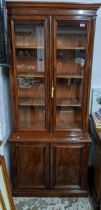 An early 20th century walnut bookcase side cupboard stepped cornice over trim glazed display doors