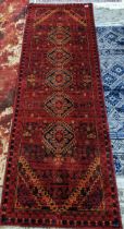 A contemporary machine woven Afghan style runner, geometric and other devices pattern, on a red