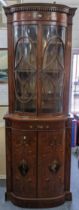 An Edwardian satinwood Sheraton Revival cabinet having bow fronted glazed doors above two cupboard