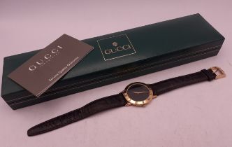 Gucci-A gents gold plated wristwatch having a black leather strap with original guarantee and box.