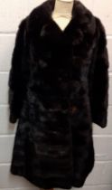 A 1960's black mink knee-length coat having 6 fur covered buttons and a black silk lining with