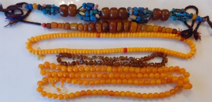 A vintage brown amber necklace together with two native necklaces of reconstructed amber and other