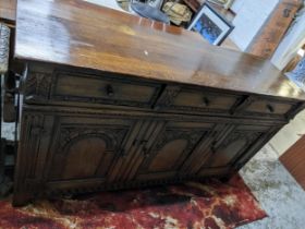 A carved oak sideboard, 20th century, three drawers above three cupboard doors having carved