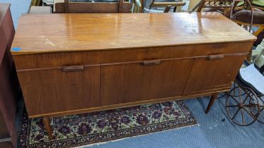 A mid 20th century teak sideboard having three drawers above three cupboard doors and tapering