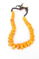 A large Moroccan pressed amber bead necklace, with graduated block beads on string, wool
