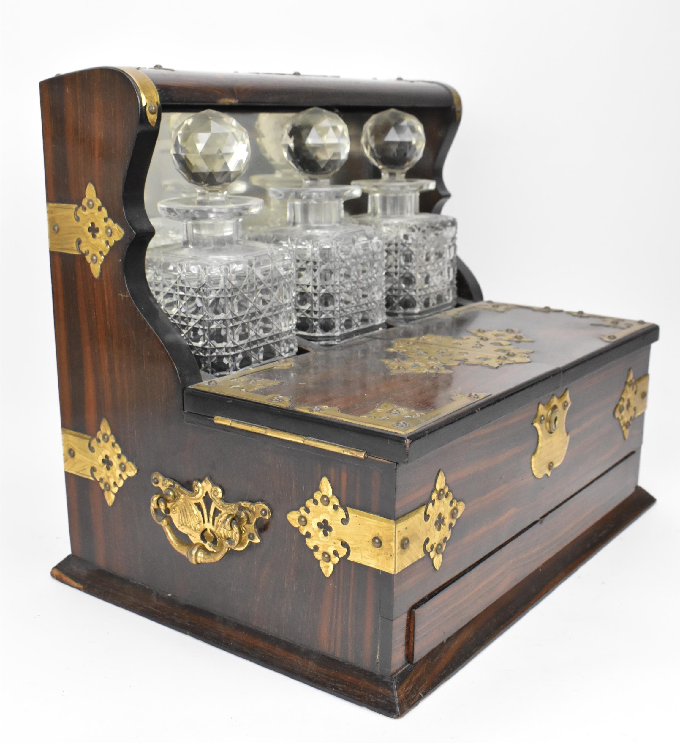 A late Victorian brass-clad coromandel veneered tantalus, comprising three cut glass decanters, - Image 2 of 3