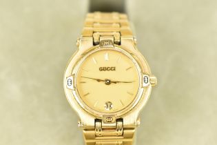 A Gucci, quartz, ladies, gold plated wristwatch, having a champagne dial with baton markers and date