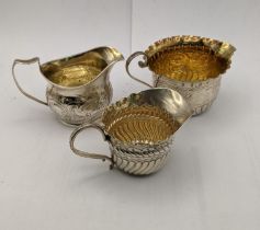 A Georgian silver cream jug and two others comprising a George II jug with floral engraved