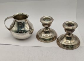 A pair of silver candlestick holders hallmarked Birmingham 1978 together with a white metal milk jug