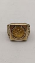 A yellow metal gents ring with a pierce design famed with a Does Pesos coin the ring stamped 14k,