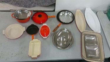 Le Creuset pots and pans to include a frying pan, serving dish and others, mostly in orange