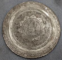 An early 20th century Middle Eastern silver coloured charger decorated with a scene of figures to