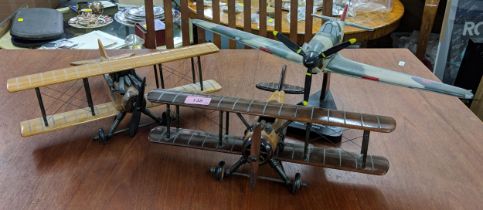 Three model planes, including two wooden bi=planes and a plastic model of a hawker Hurricane on a