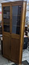 A 19th century pine corner cabinet, twin glazed doors, with shaped internal shelves, over twin