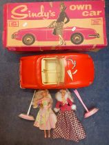 A boxed vintage red Sindy car A/F in original box and 2 late 20th Century Barbie dolls on stands