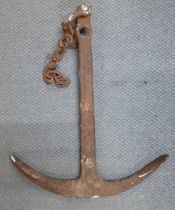 A vintage wrought iron ship's anchor with partial chain Location: