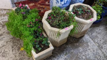 A pair of octagonal garden composite stone planters with vertical fluted design on shaped plinth