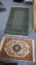 Two hand woven rugs to include a Pakistani green ground rug with multi-guard borders and tasselled
