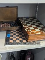 An inlaid wooden chess board with marble chess pieces, together with a marble chess board and marble