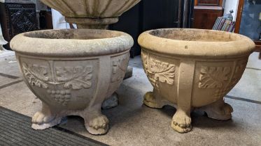 A pair of composition garden planters of circular form, moulded decoration and raised on four paw