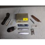 A group of pen fruit knives, cigar cutters, penknives, and a silver plated cigarette box Location: