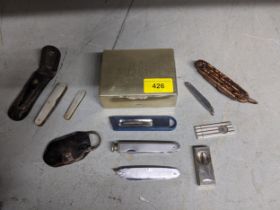 A group of pen fruit knives, cigar cutters, penknives, and a silver plated cigarette box Location: