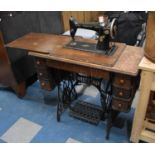A Manual Singer Sewing Machine on Stand with Wooden Top having Three Drawers Flanking Cast Iron