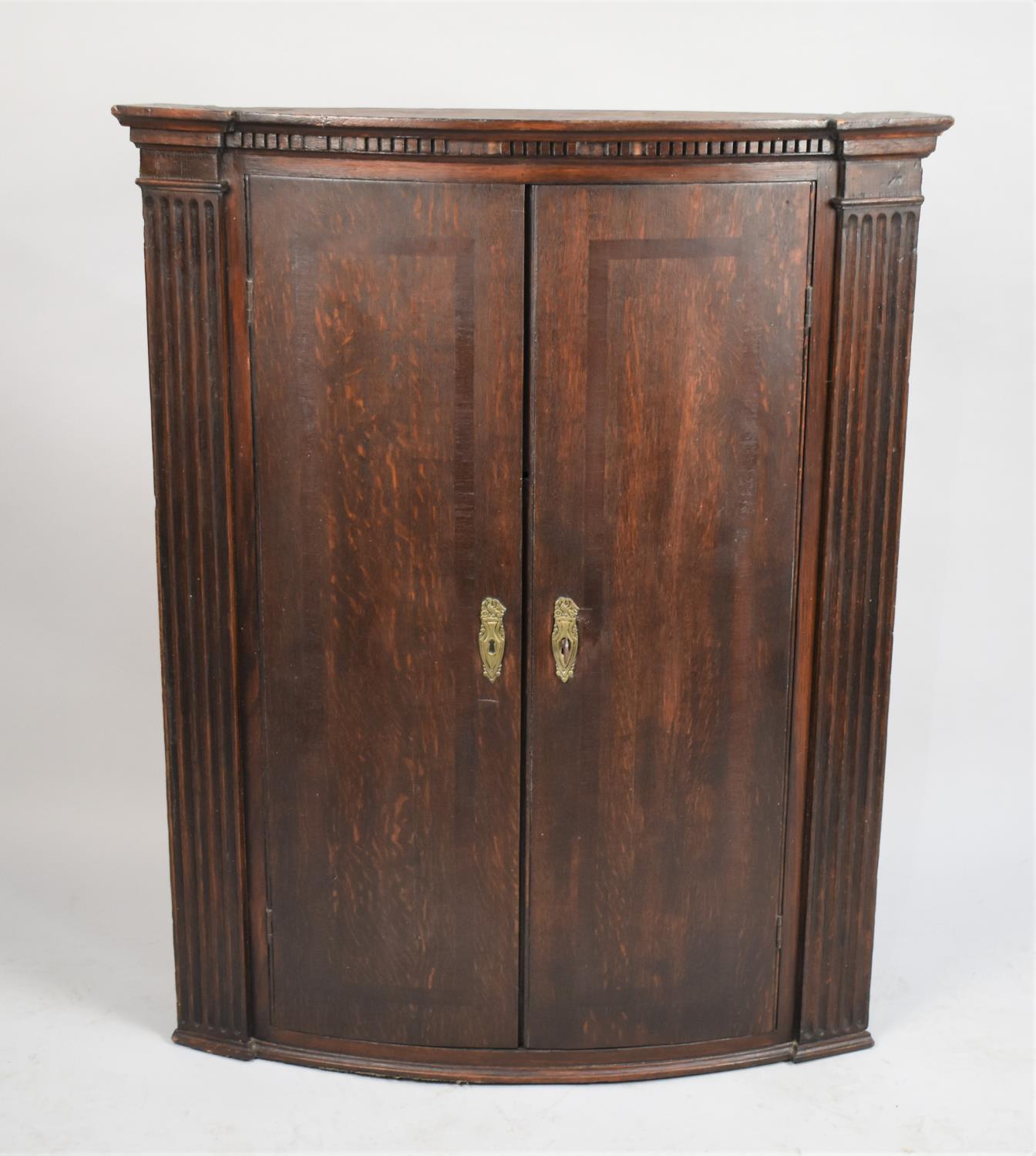 A Late 19th Century Oak Bow Fronted Wall Hanging Corner Cabinet with Shelved Interior and Dentil