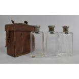 An Edwardian Leather Case Containing Three Glass Flasks with Silver Plated Tops, 14cms High