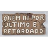 A Carved and Painted Portuguese Sign, He Who Laughs Last..., 35cm wide