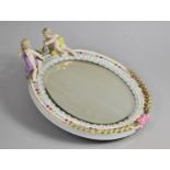 A Porcelain Oval Easel Back Mirror with Polychrome Enamels and Cherub Finials, 28cms High
