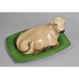 A London Pottery Novelty Butter Dish and Cover in the Form of a Recumbent Cow on Green Stylised