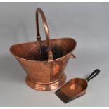 A 20th Century Hand Beaten Copper Helmet Shaped Coal Scuttle and a Wooden Handled Scoop