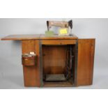 A Walnut Cased Singer Treadle Sewing Machine, Cabinet Water Damaged, With Accessories