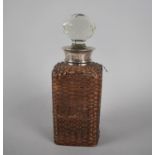 A Glass and Silver Cuffed Decanter with Wicker Case, 23cm high