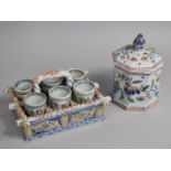 A Tin Glazed Faience Egg Cruet in Basket Stand and Six Egg Cups Together with a Lidded Pot