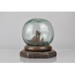 A Late 19th Century Folk Art Glass Fishing Float Containing a Miniature Ships Diorama, Supported