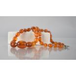 A String of 35 Vintage Orange Amber Beads, Largest 18mm by 13mm, 44cms Total Length, 17.8gms