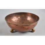 An Arts and Crafts Hammered Copper Bowl, C.1915, Raised on Three Ball Feet with Rope Work Rim.