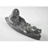 A Moulded Resin Inuit Style "Stone Carving" of Eskimo in Canoe with Seal Pup and Fish, 26cm Long