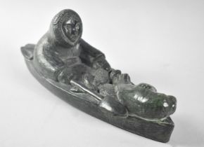 A Moulded Resin Inuit Style "Stone Carving" of Eskimo in Canoe with Seal Pup and Fish, 26cm Long